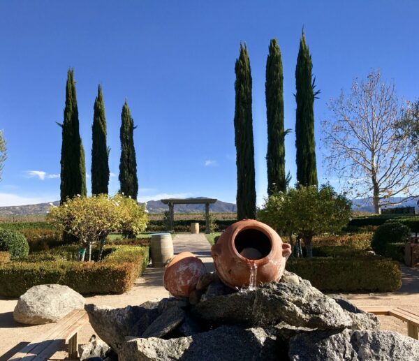 A vase sitting on top of rocks in front of trees.