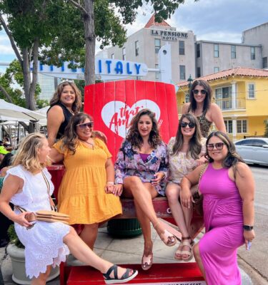 A group of women sitting on top of a red truck.